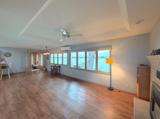 Spacious living room featuring a box vault ceiling, gas fireplace and an impressive stretch of windows that keeps the lake in view throughout the room.