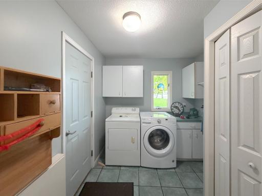 Convenient main-level laundry room with washer and dryer, built-in cabinetry and additional counter space for everyday storage and organization.