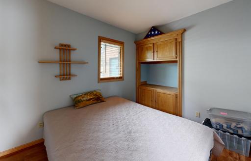 Comfortable main-level bedroom featuring warm wood trim and a built-in cabinet offering convenient storage and display space.