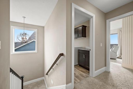 Laundry room includes a utility sink, stone countertop, and additional cabinetry.