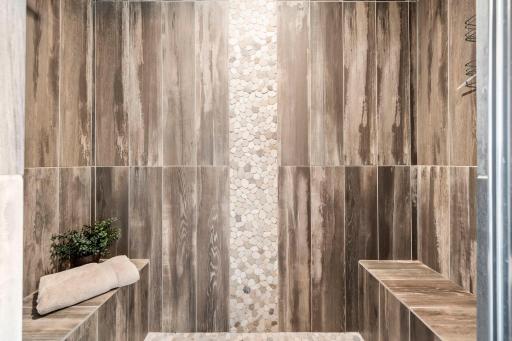 Built-in shower benches and pebble-tile flooring create a true spa-like experience.