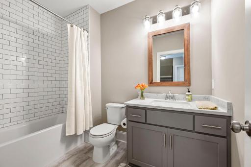 Spacious lower-level full bath features classic white subway tile extending to the ceiling.