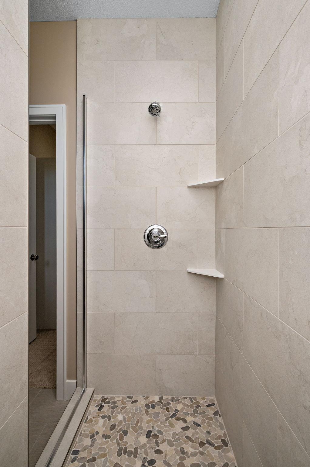 Spacious shower tiled to the ceiling and includes a bench (not shown)