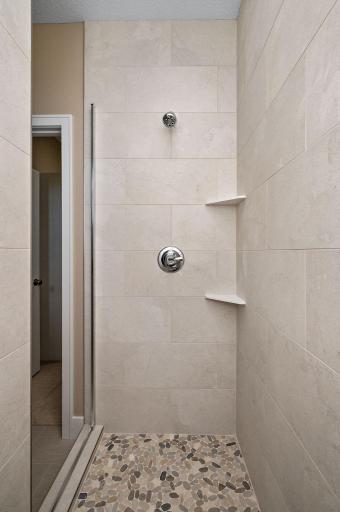 Spacious shower tiled to the ceiling and includes a bench (not shown)