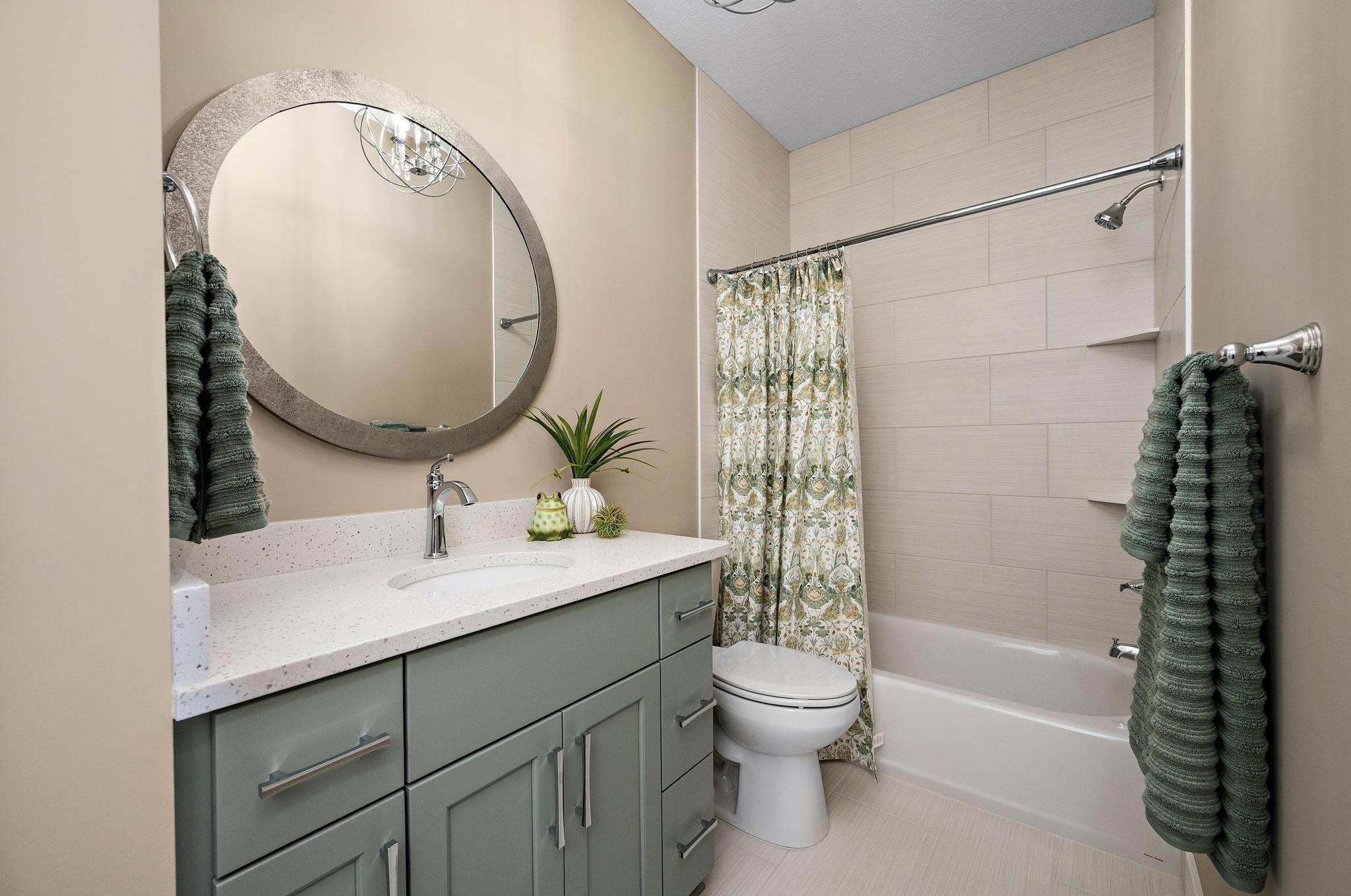 Main level full bath with tile to the ceiling and quarts countertop- also includes a linen-Not shown in photo.