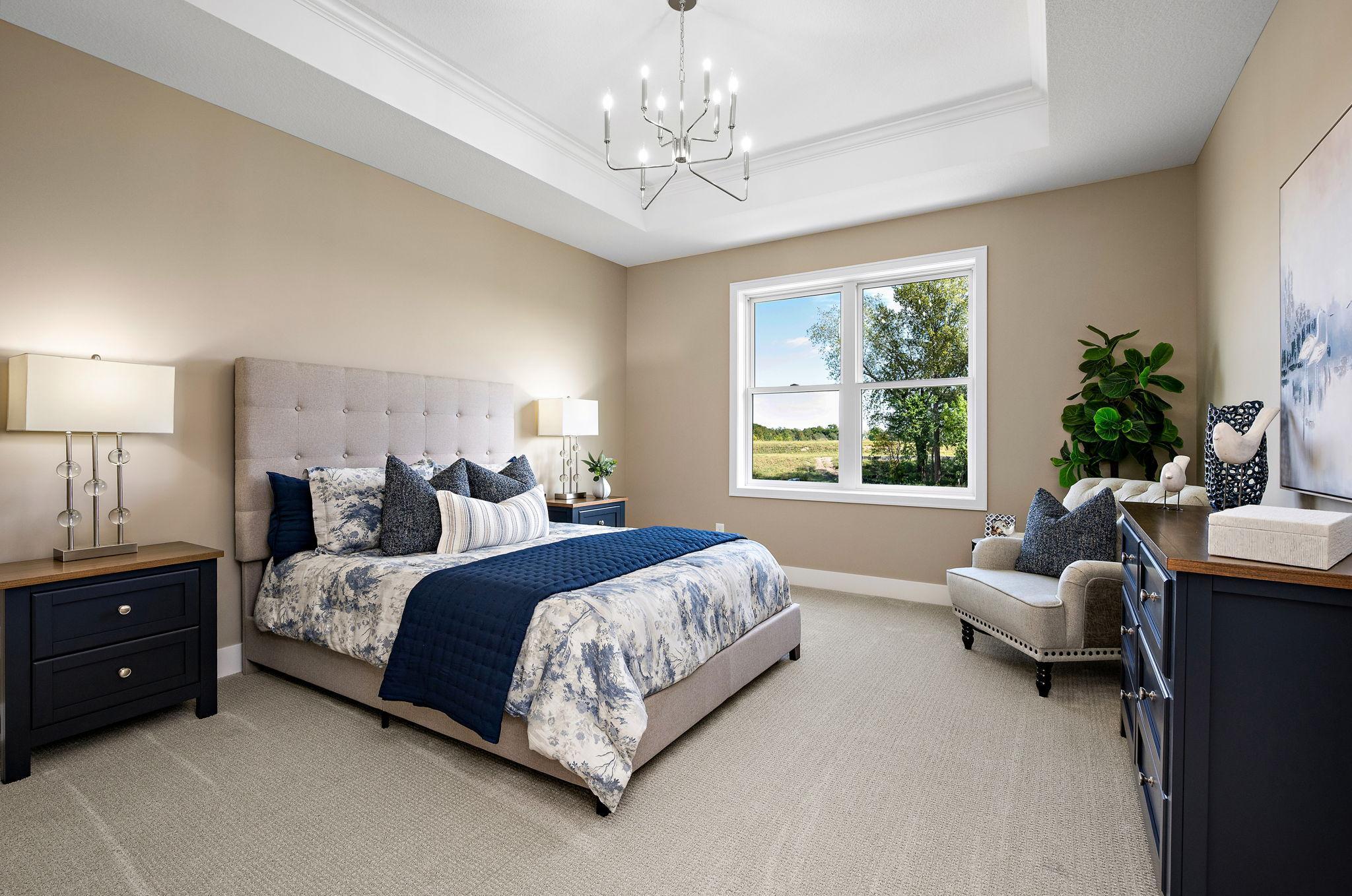 Owners suite with vaulted ceiling, crown molding, textured carpet and pretty views of the pond and trees.