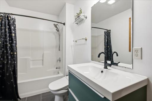 Full bathroom with a tub/shower combination, modern vanity, and a large mirror.