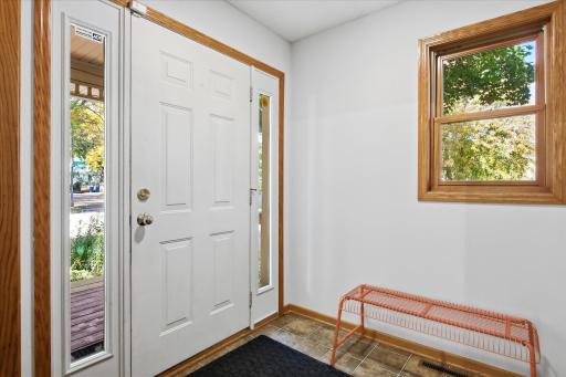 The bright and inviting entryway features natural wood trim, a large window, and easy access to the front porch.