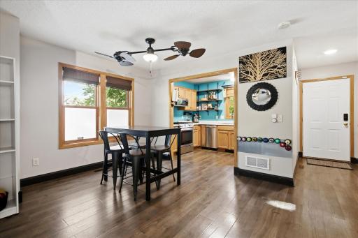 Bright dining area with large windows and warm wood flooring, opening naturally to the kitchen.
