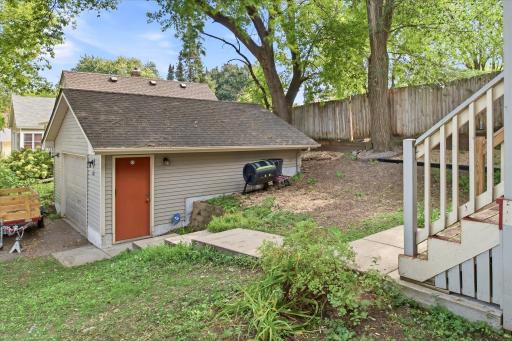 This home features a detached garage complemented by a generous side yard and paved walkway, offering practical access and additional outdoor space.