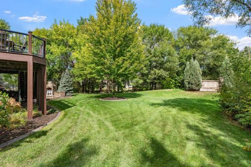 The expansive, level lawn is framed by lush greenery and mature trees, creating a beautiful backyard setting.