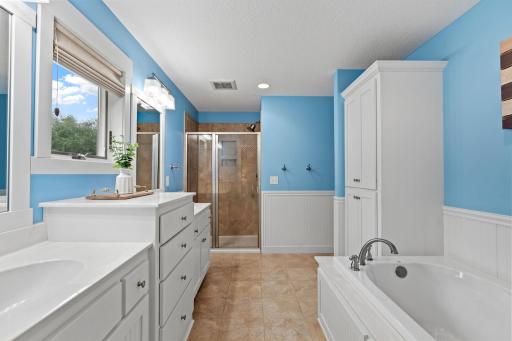 The private primary bath offers a spacious layout with a separate soaking tub, tiled shower, and abundant cabinetry.