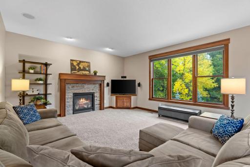 The spacious living room is anchored by a beautiful stone-surround gas fireplace and framed by large windows overlooking the mature backyard.