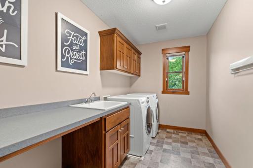 Conveniently located alongside the bedrooms, the upper-level laundry room includes a utility sink, generous folding counter, cabinetry, and a wall-mounted drying rac