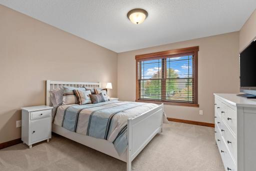 A spacious secondary bedroom features a large window, generous natural light, and ample closet space.