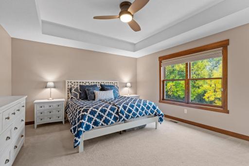 The spacious primary suite features a beautiful tray ceiling, large windows, and peaceful views of the mature backyard.
