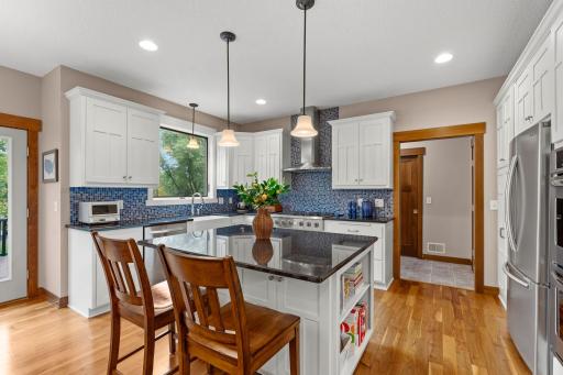 The center island offers additional prep space and breakfast-bar seating, complemented by pendant lighting and extensive cabinetry throughout.