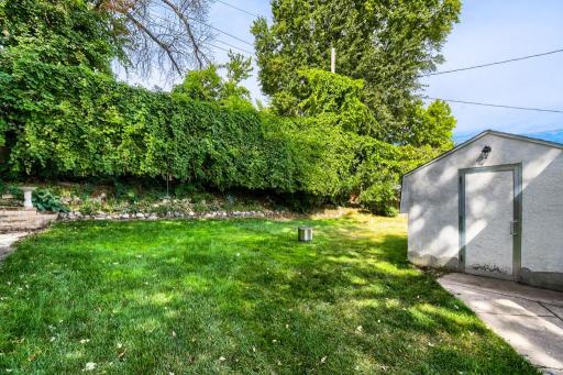 Beautiful private backyard surrounded by mature greenery, with a large storage shed for tools, equipment, and seasonal items.