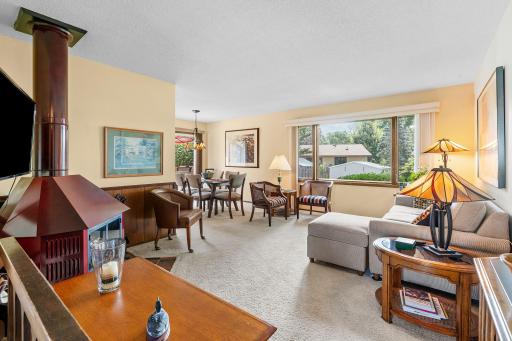 The open living and dining area flows around a stunning vintage mid-century modern freestanding wood fireplace and a custom built-in hutch with glass-front display storage.