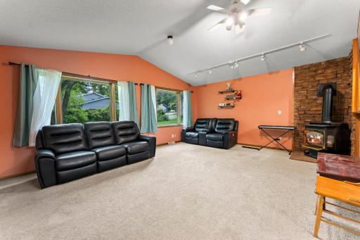 Living Room with vaulted ceiling, gas fireplace and chimney and stone accent wall