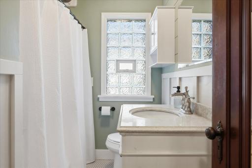 Updated full bathroom with a glass block window, newer vanity, mirror, faucet and fixtures.