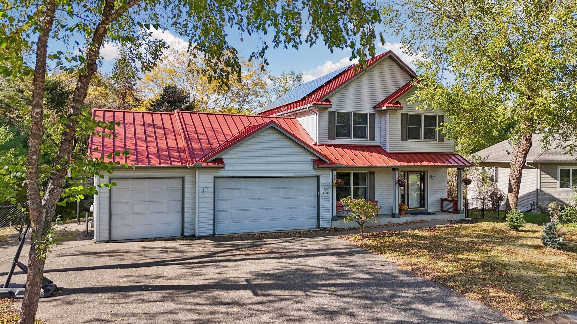 A striking red metal roof with solar panels adds character and efficiency, while the charming covered front porch offers a warm welcome home.