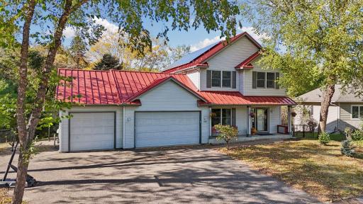 A striking red metal roof with solar panels adds character and efficiency, while the charming covered front porch offers a warm welcome home.