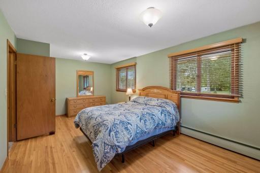 The generous main floor primary bedroom features hardwood floor, two closets, multiple windows, and plenty of space for a comfortable bedroom retreat.