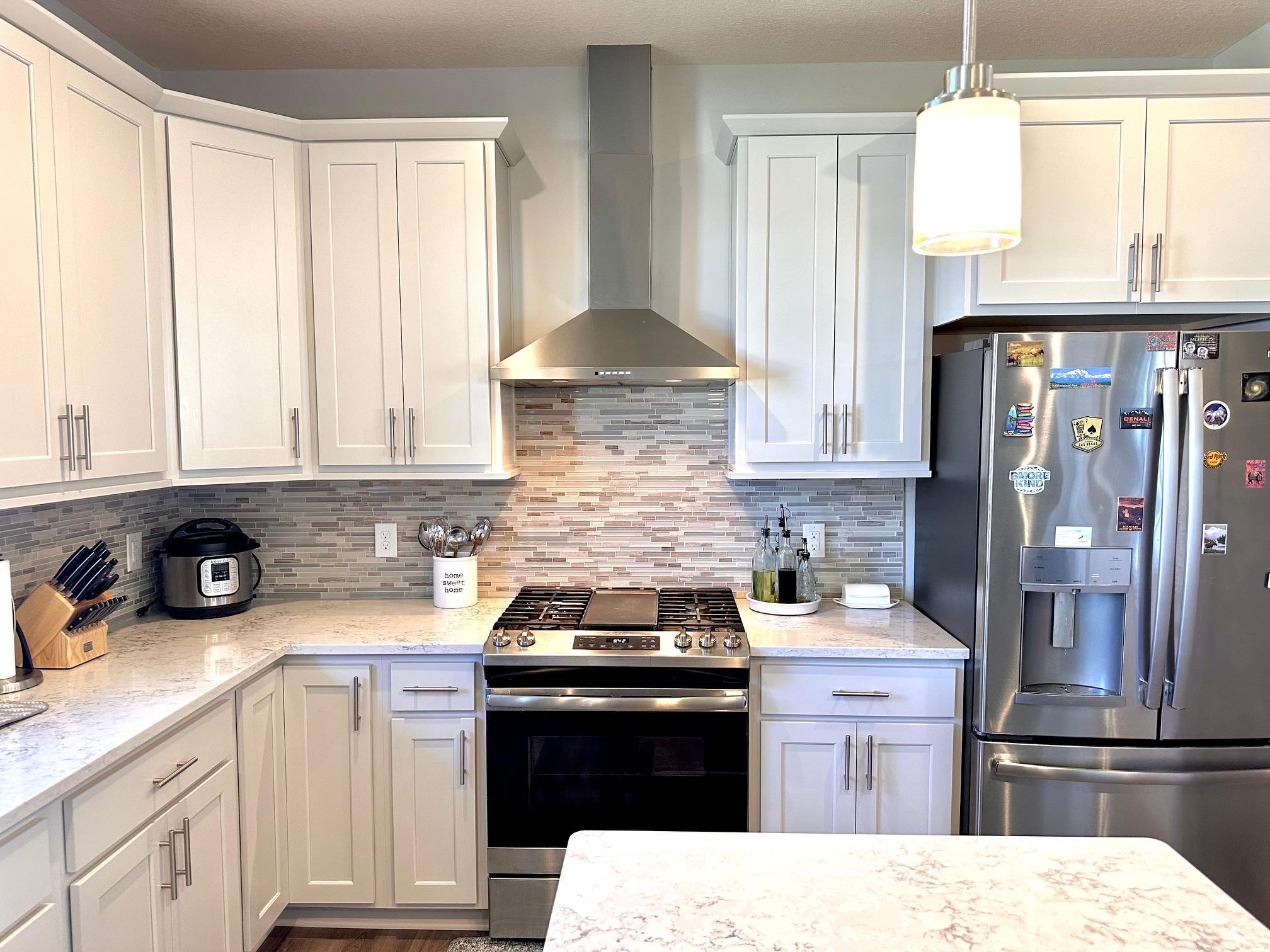 Beautifully appointed kitchen with quartz countertops, stainless steel appliances and range hood.jpeg