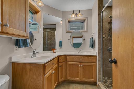 The updated primary bath features dual windows, dual sinks, an angled corner vanity, and linen storage.