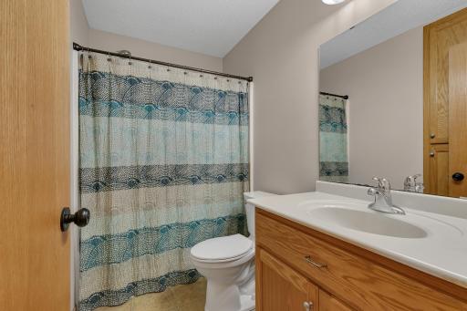 Full bathroom featuring a built-in linen cabinet, a raised oak vanity and a new toilet Jan 2026.