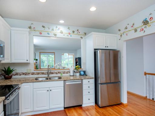 Spacious kitchen features hardwood floors, tile backsplash, granite countertops and stainless steel appliances. A convenient pass-through window creates an open, connected feel to the adjoining living and dining space.