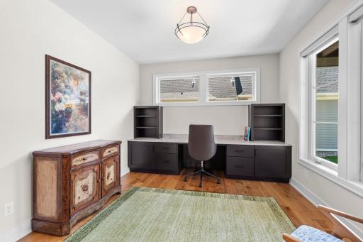 Front office off the foyer features a convenient built-in desk, charming French doors, and views overlooking the front patio.