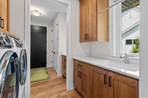 Convenient laundry room with sink and side yard views, located between the mudroom and kitchen.