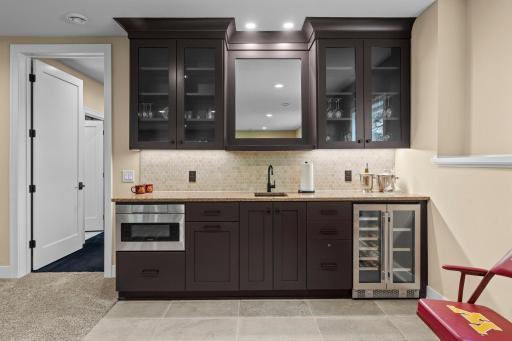 Wet bar with sink, microwave, and beverage fridge, creating a convenient setup for entertaining and hosting.