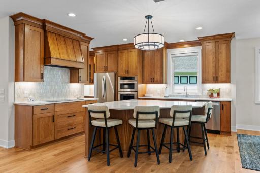 Chef-inspired kitchen featuring oversized windows, a stunning tile backsplash, and warm natural finishes.