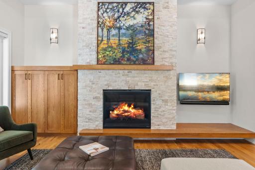 Beautiful stone fireplace framed by custom-built shelving on one side in the living room.