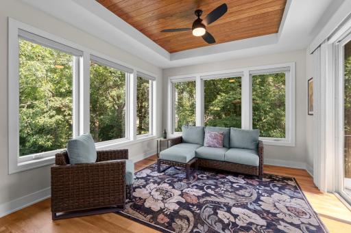 Sunroom surrounded by windows and natural light, with views of the side and backyard and direct access to the deck.