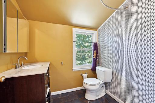 Upper-level 3/4 bathroom that has been recently remodeled with penny tiled shower, tiled flooring and stone countertops.