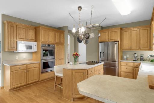 Generously sized Kitchen offers an abundance of cabinetry and counter space, a center island with seating, built-in double wall ovens and a separate cooktop. The refrigerator and double ovens were replaced in 2022 and the cooktop was updated in 2024.