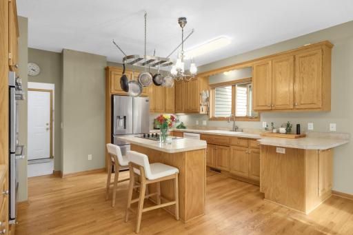 Large Kitchen offers an abundance of cabinetry and counter space, plus a center island with cooktop and seating. Hardwood flooring and a window above the sink add to the bright, comfortable workspace.