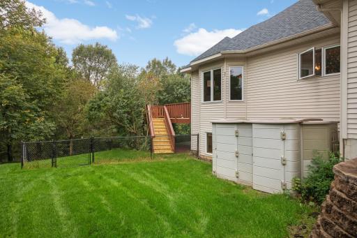 Rear view of the home shows the spacious deck and mature trees that surround the property.