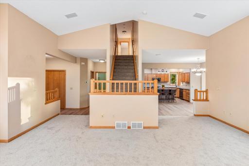 Here's a view of the foyer, stairs, dining, & kitchen from the great room. This landing at the bottom on the stairs & the railings shown were custom-added when this home was built.