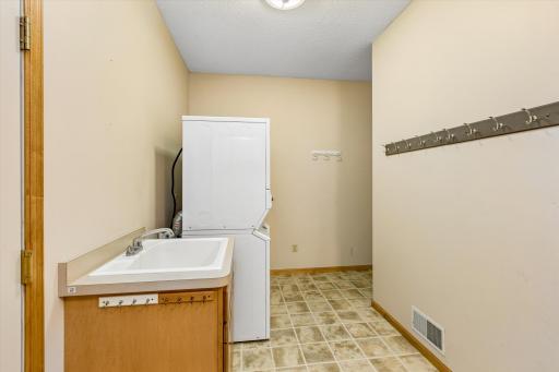 The very spacious laundry room with two stackable washer/dryers, sink, loads of space, closet, and entrance to the garage.