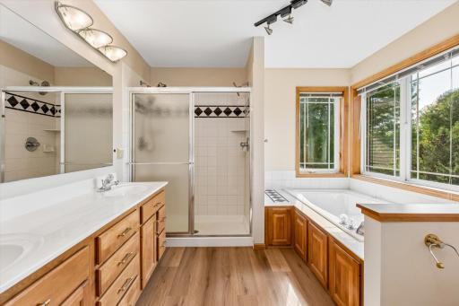 And spacious primary BA with jettied tub, separate ceramic shower with dual shower heads, large vanity, and brand-new vinyl/plank flooring.