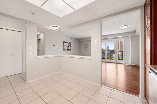 Open dining area flows into the spacious living room, where large windows and balcony doors showcase city views and natural light.