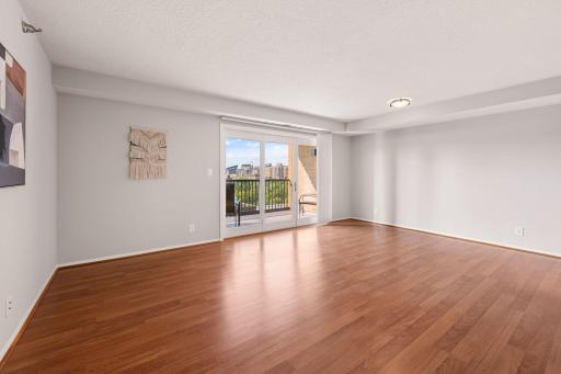 Spacious living room with warm-toned flooring, neutral finishes, and access to the private balcony.