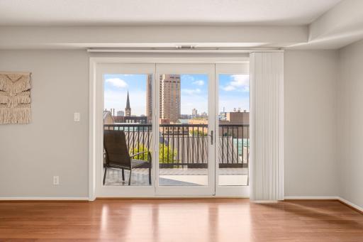 Large glass doors frame neighborhood and city views while providing direct access to the private balcony.