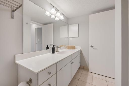 Spacious bathroom features a long vanity, generous counter space, ample cabinetry, and a large wall mirror.