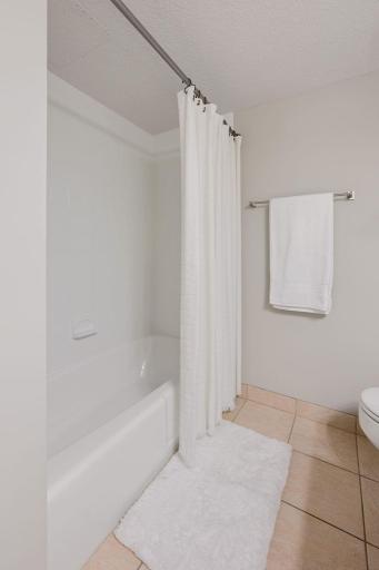 Fresh and inviting full bathroom features a clean tub-and-shower combination and easy-care tile flooring.